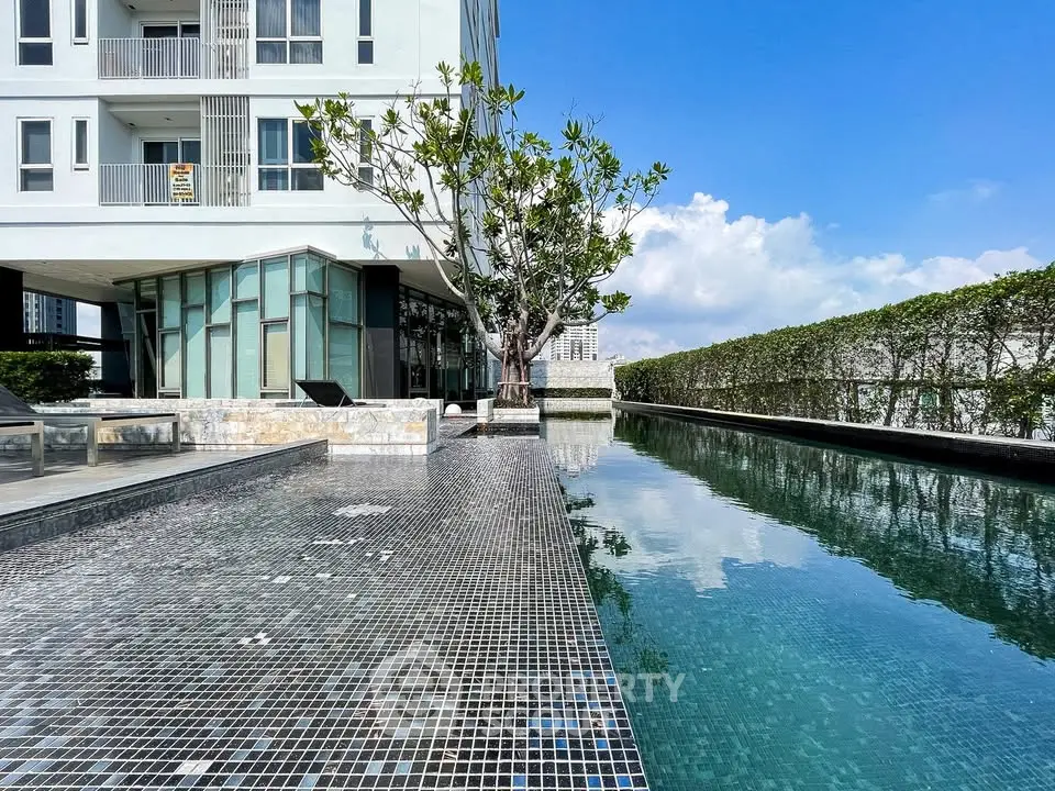 Luxurious modern apartment building with stunning pool and lush greenery, perfect for relaxation and leisure.
