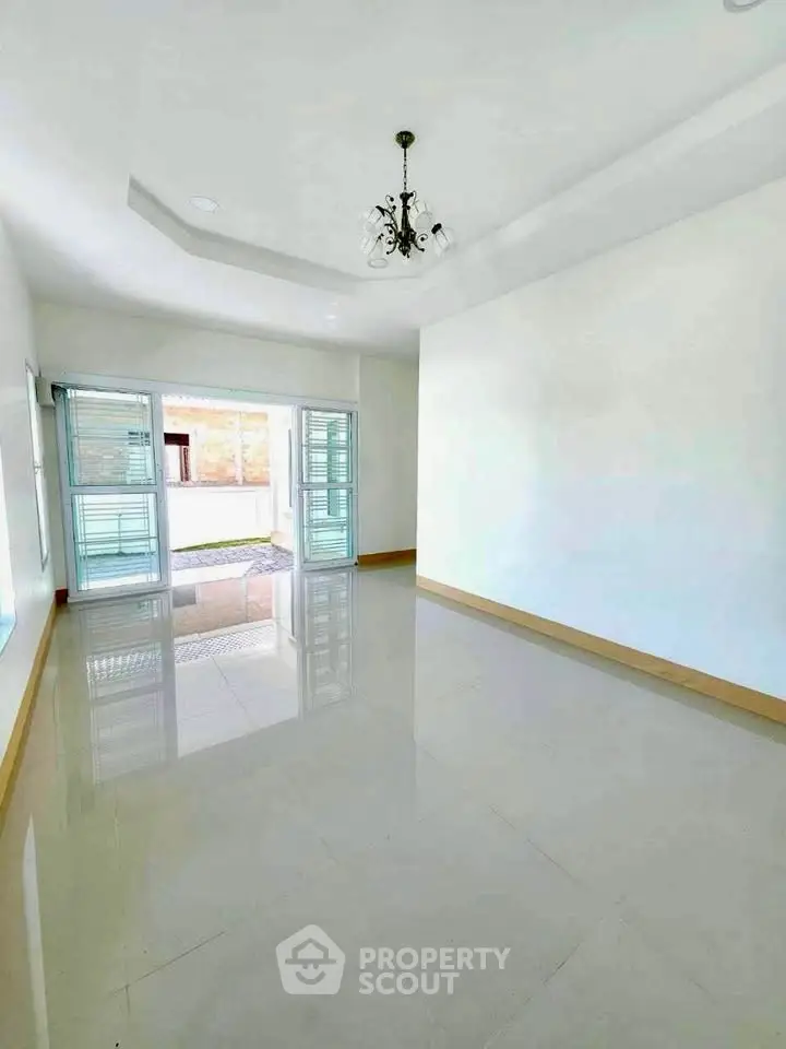 Spacious and bright living room with large windows and elegant chandelier.