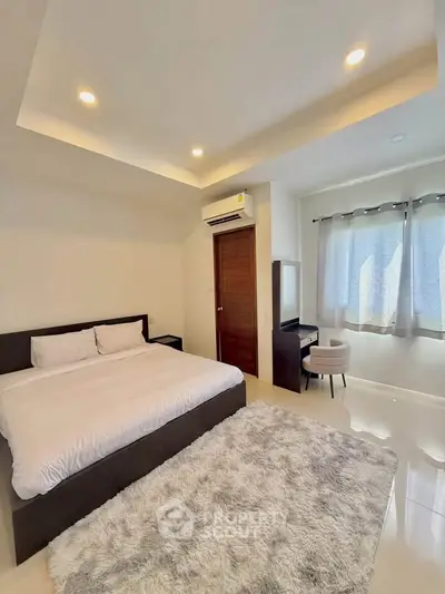 Spacious bedroom with modern decor and cozy ambiance, featuring a plush rug and ample natural light.