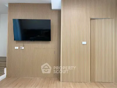 Modern living room with sleek wooden paneling and wall-mounted TV