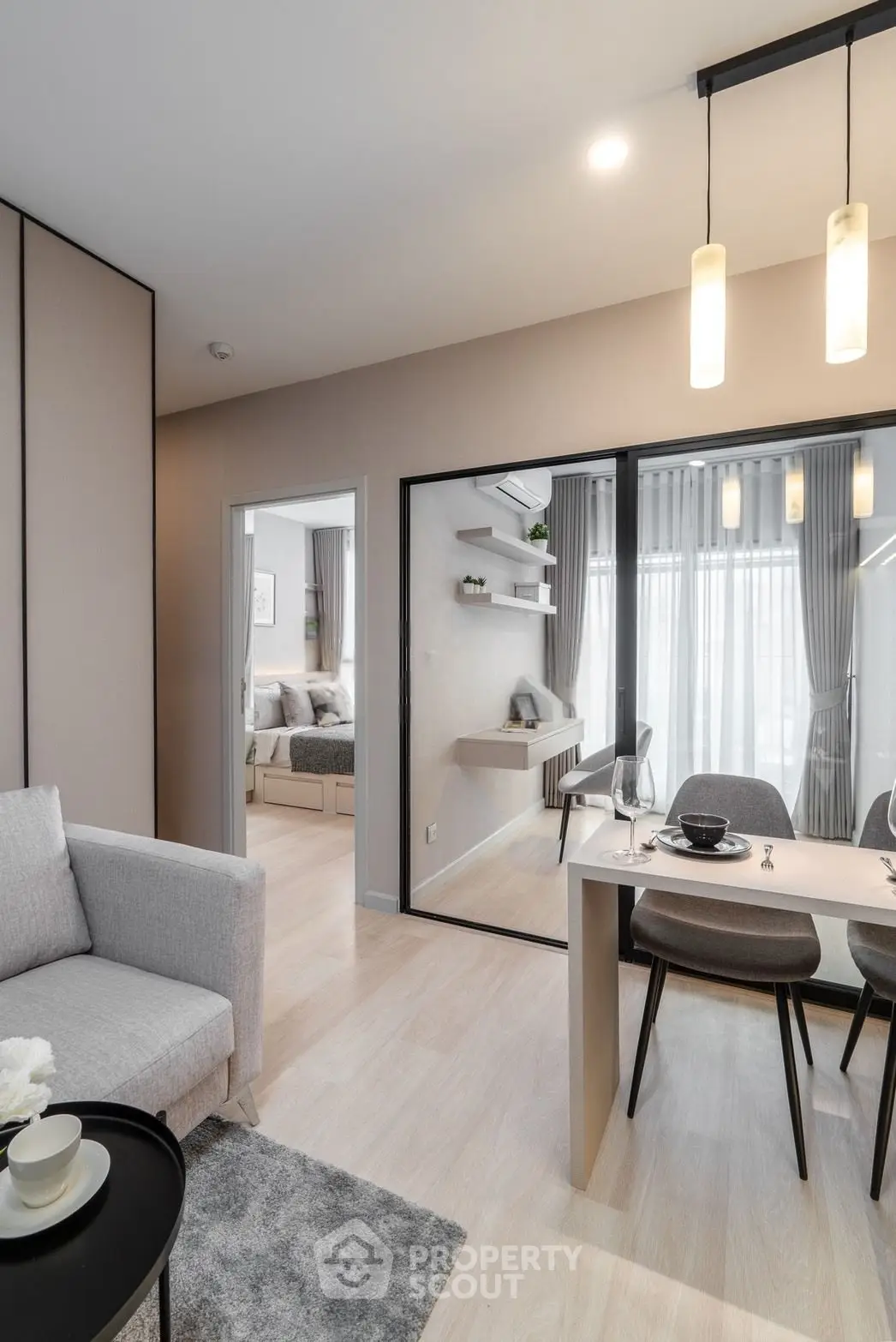 Modern open-plan living room with dining area and view into a stylish bedroom, featuring elegant decor and natural light.