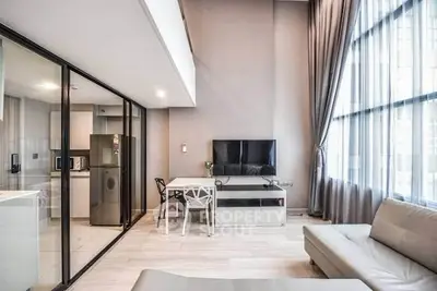 Modern living room with open kitchen and large windows in stylish apartment.