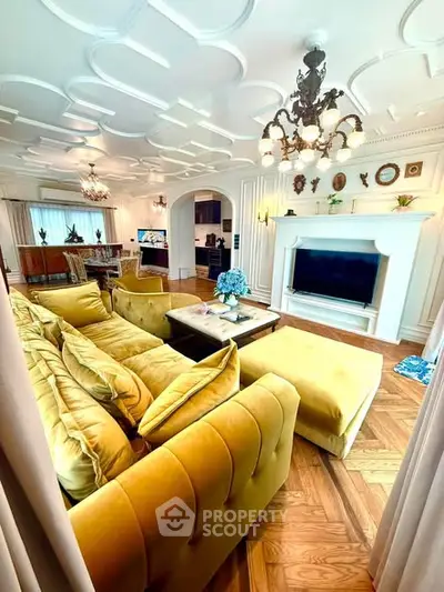 Luxurious living room with elegant decor, plush yellow sofa, and ornate ceiling in a spacious open layout.