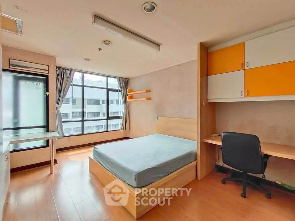 Modern bedroom with large window and built-in desk in urban apartment
