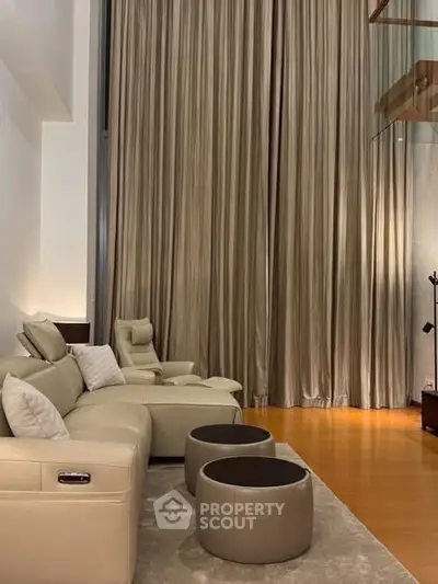 Luxurious living room with high ceilings and elegant drapery, featuring plush seating and modern decor.