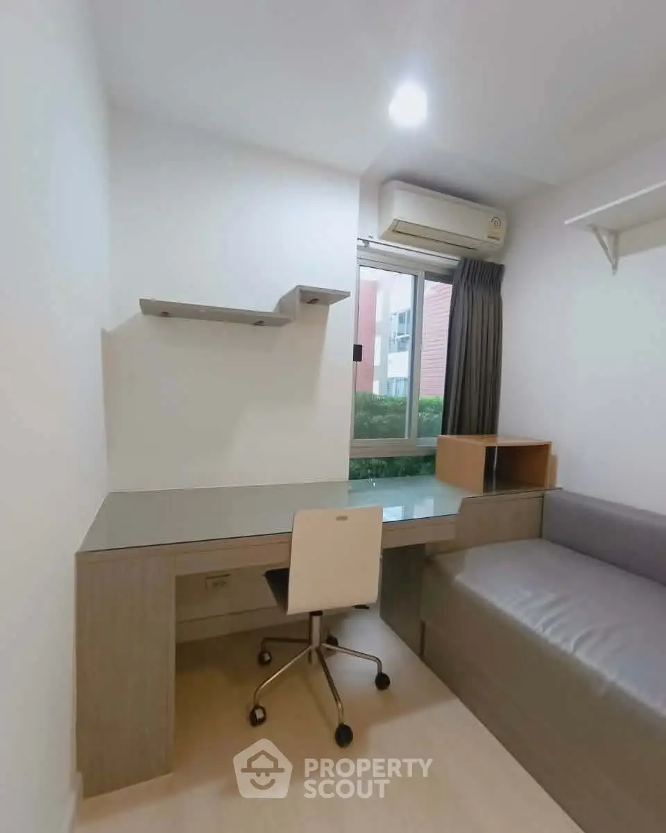 Modern study room with sleek desk, chair, and window view in a cozy apartment.