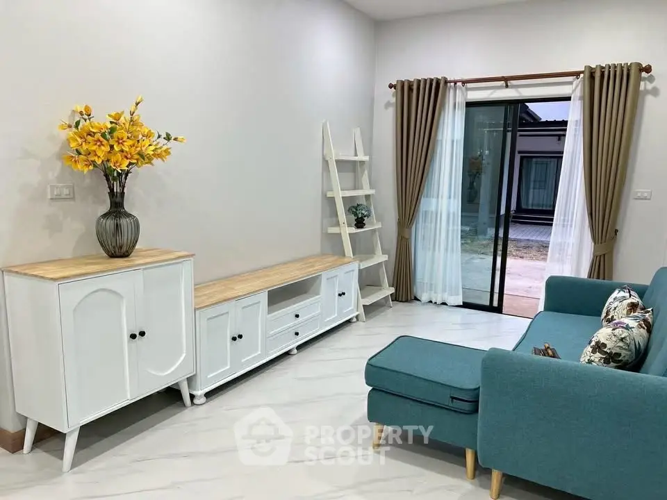 Charming living room with modern furniture and sliding glass doors leading to a serene outdoor view.