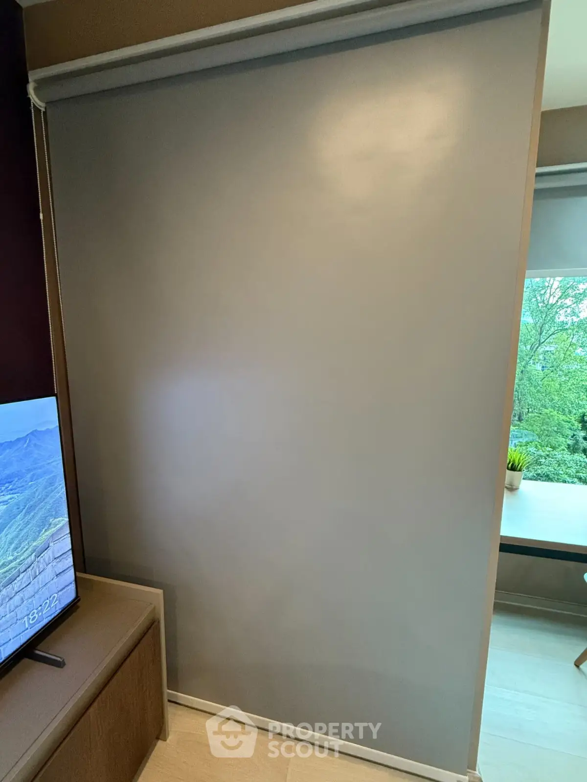 Modern living room with sleek TV stand and large window offering lush green view.