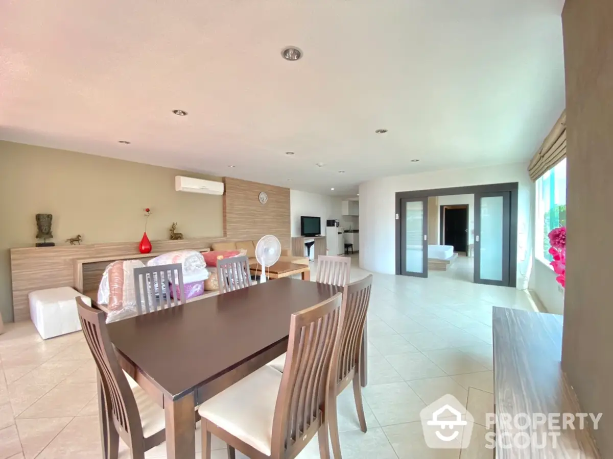 Spacious and modern open-plan living area with elegant dining set, sleek kitchen, and abundant natural light, perfect for entertaining and family living.