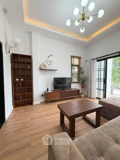 Stylish living room with modern decor, wooden flooring, and large windows opening to a lush garden view.
