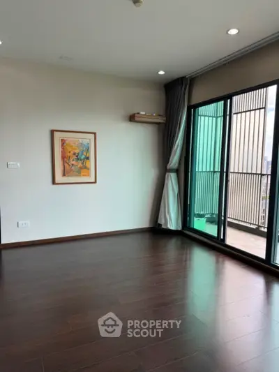Spacious living room with wooden flooring and balcony access in modern apartment
