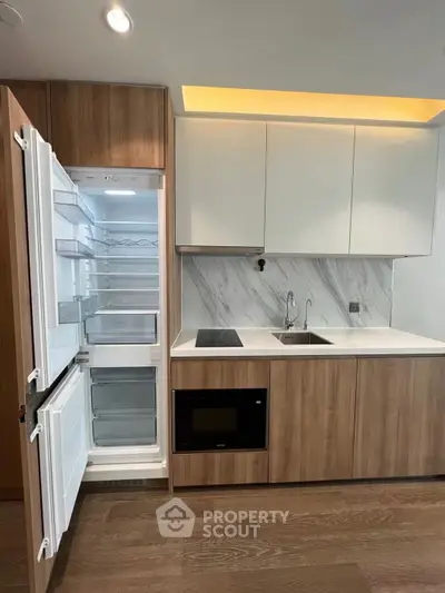 Modern kitchen with open fridge, sleek cabinetry, and built-in appliances in a stylish apartment.
