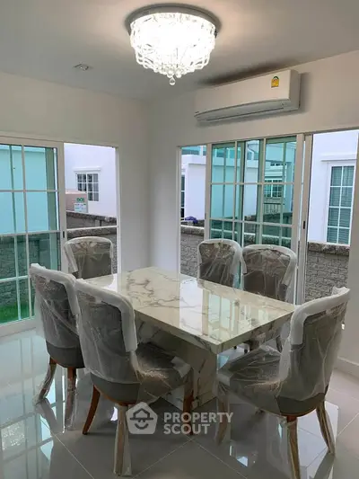 Elegant dining room with marble table and modern chandelier in a bright, airy space.