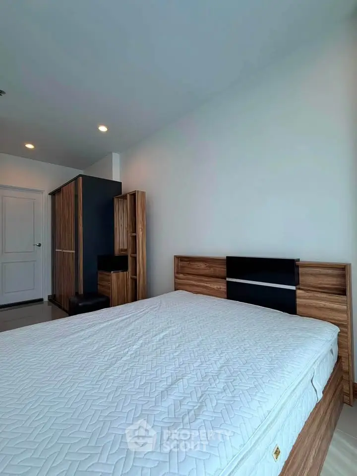 Spacious bedroom with modern wooden furniture and ample natural light.
