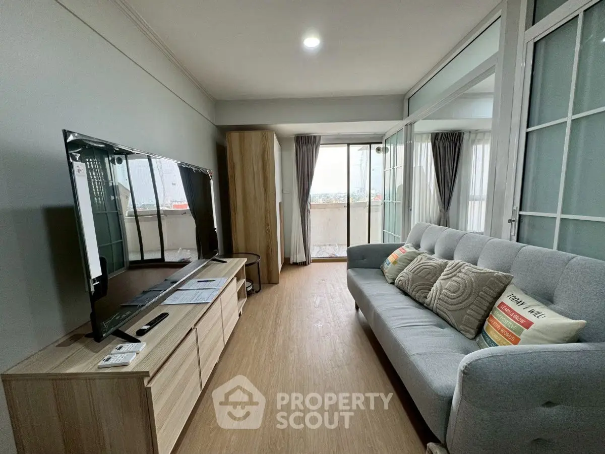 Modern living room with sleek TV and cozy sofa, featuring a balcony view.