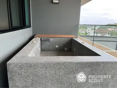 Modern balcony with concrete bathtub and glass railing offering scenic views.