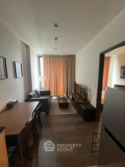 Modern living room with stylish furniture and large window draped with curtains, creating a cozy ambiance.
