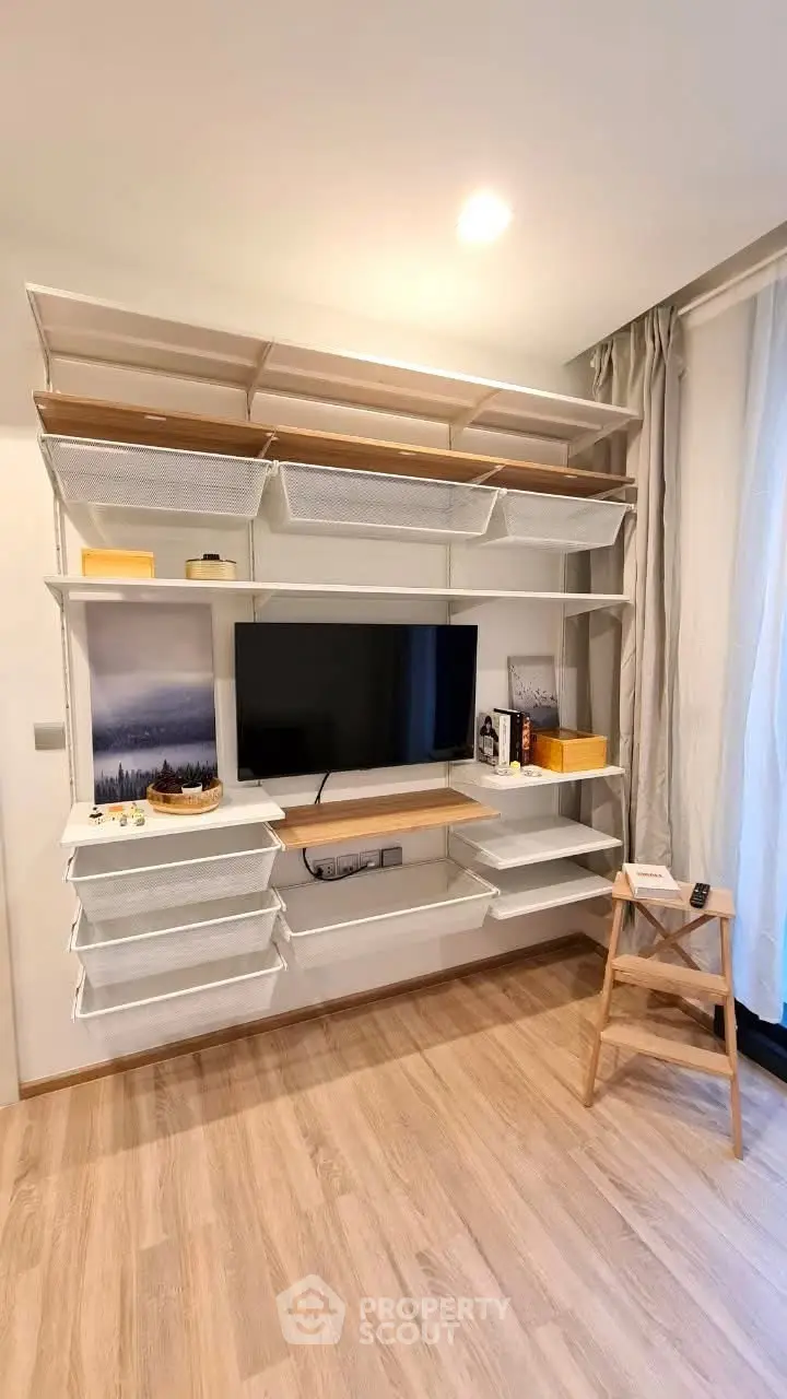 Modern living room with stylish shelving and TV setup, featuring elegant decor and natural light.