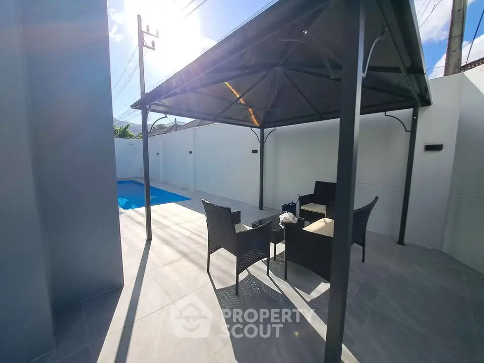 Modern outdoor patio with pool and stylish furniture under a sleek gazebo.