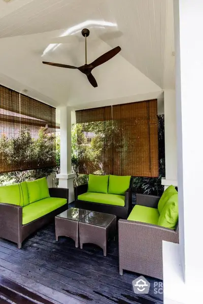 Charming outdoor patio with green cushioned seating and ceiling fan