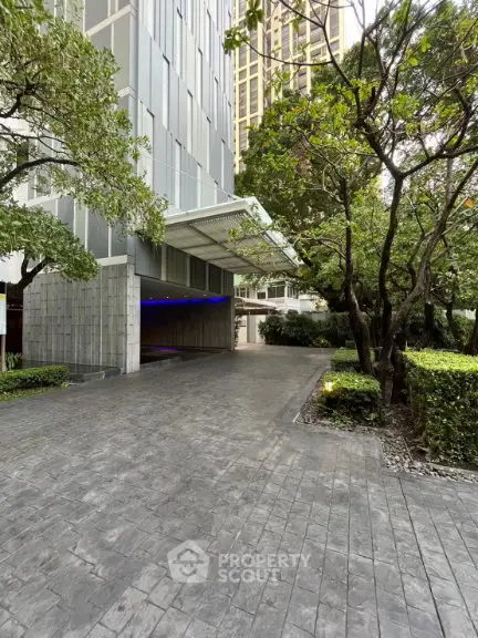 Modern building entrance with lush greenery and spacious driveway