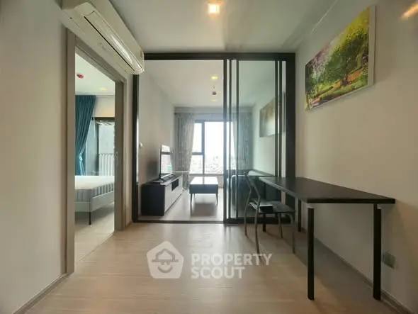 Modern apartment interior with glass partition, sleek furniture, and natural light.