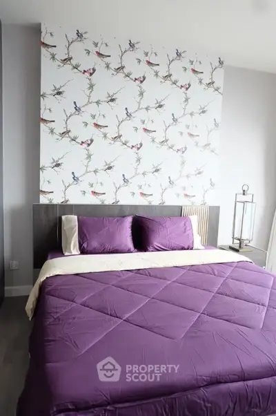 Stylish bedroom with vibrant purple bedding and bird-themed accent wall