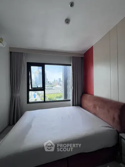 Modern bedroom with city view and large window in urban apartment.