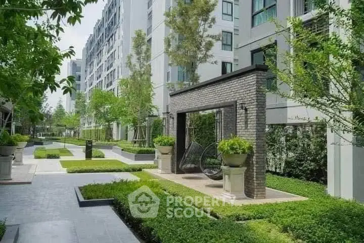 Modern apartment complex with lush green garden and stylish outdoor seating area.