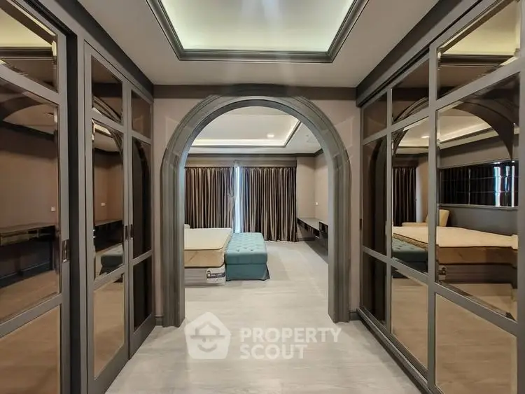 Luxurious bedroom with mirrored closets and elegant archway entrance.