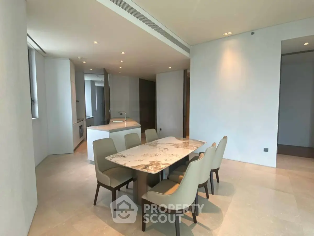 Spacious dining area with elegant marble table and modern chairs in a luxurious apartment.