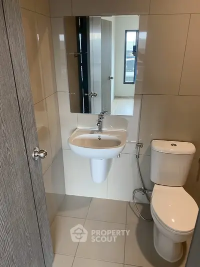 Modern bathroom with sleek fixtures and neutral tiles, featuring a compact design for efficient space use.