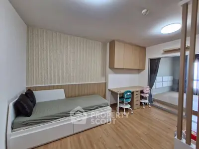 Modern bedroom with wooden flooring, built-in desk, and ample storage space.