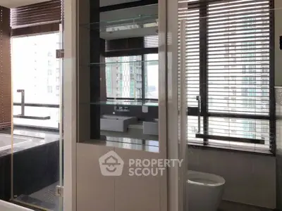 Modern bathroom with large windows and sleek fixtures in high-rise apartment.