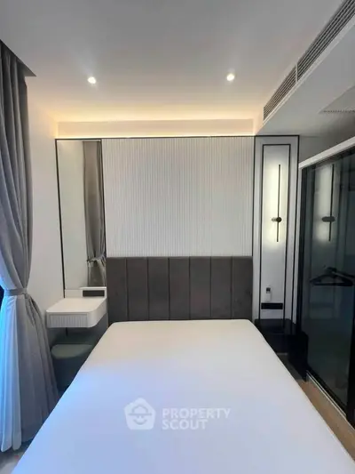 Modern bedroom with sleek design, featuring a large bed, stylish lighting, and elegant curtains.