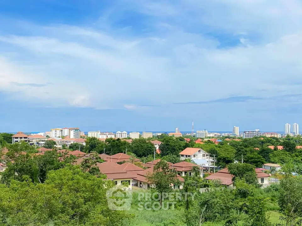 Stunning panoramic view of a lush green neighborhood with red-roofed houses and city skyline in the distance.