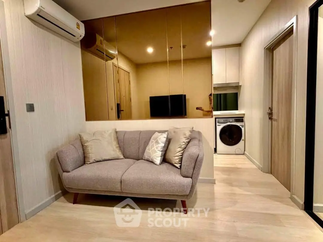 Modern living room with cozy sofa and integrated laundry area in stylish apartment.