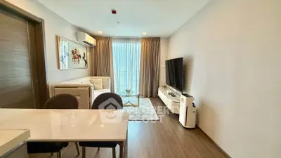 Modern living room with stylish decor, large TV, and natural light from floor-to-ceiling windows.