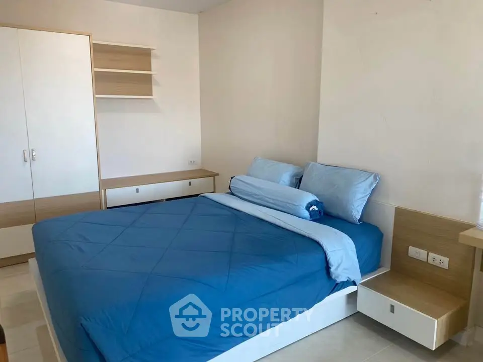 Modern bedroom with blue bedding and built-in storage in a stylish apartment.