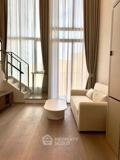 Spacious living room with high ceilings and large windows, featuring modern furniture and elegant curtains.