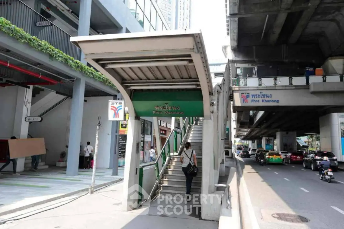 Modern urban entrance to Phra Khanong BTS station with street view and nearby buildings.