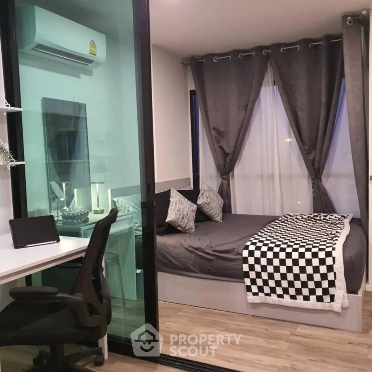 Modern bedroom with stylish decor and workspace, featuring large windows and cozy ambiance.
