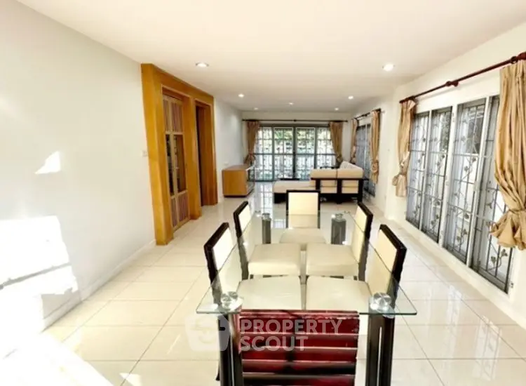 Spacious open-plan living and dining area with large windows and modern decor.