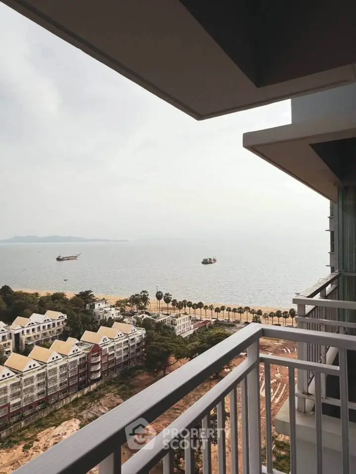 Stunning ocean view from a high-rise balcony overlooking beachfront properties and palm-lined shore.
