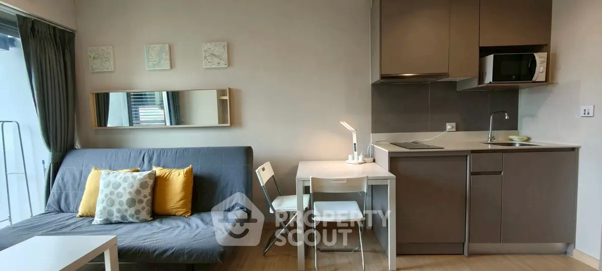 Modern compact studio apartment with cozy living area and sleek kitchen design.