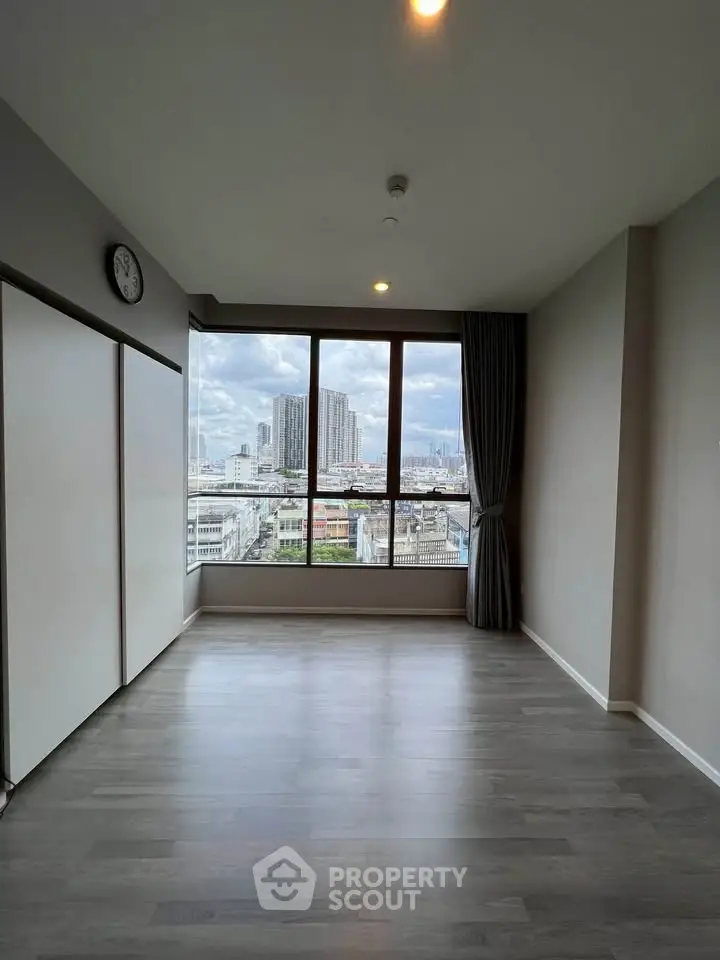 Spacious room with large window offering stunning city view, perfect for modern living.