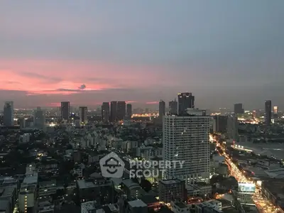 Stunning cityscape view at dusk with illuminated skyline and vibrant sunset hues.