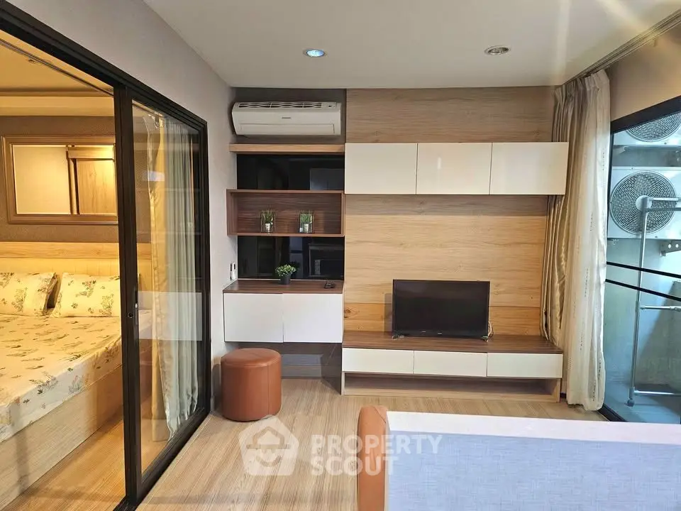 Modern living room with stylish wooden accents and sliding glass door to bedroom.