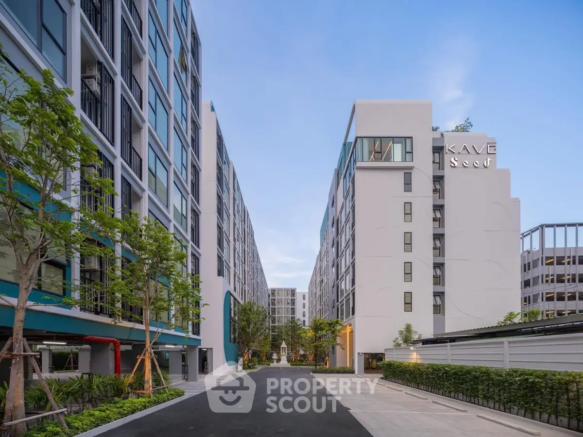 Modern apartment complex with sleek architecture and lush landscaping under a clear blue sky.