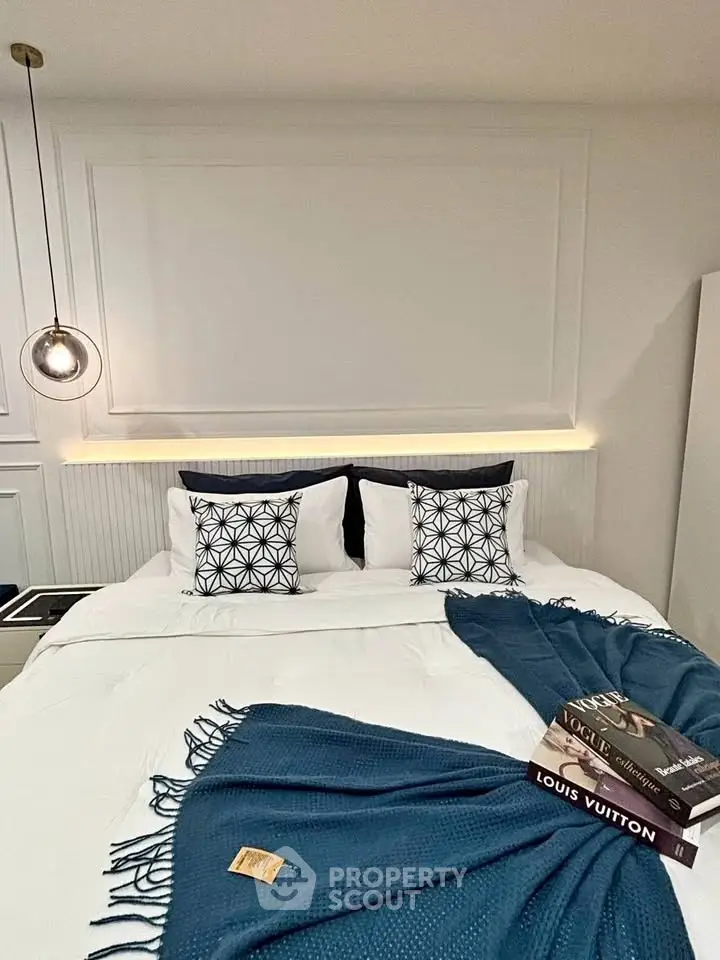 Luxurious bedroom with elegant decor and designer books, featuring stylish lighting and plush bedding.